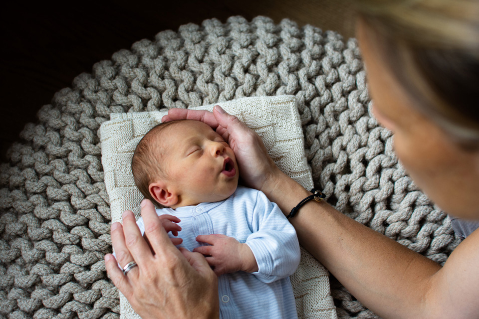 Mama streichelt dem schlafenden Baby den Kopf.